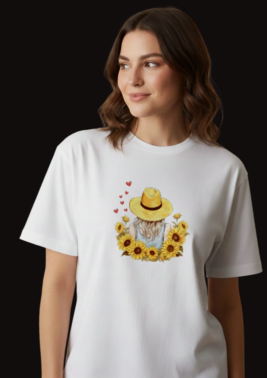 Woman wearing a white t-shirt with a sunflower design and straw hat.