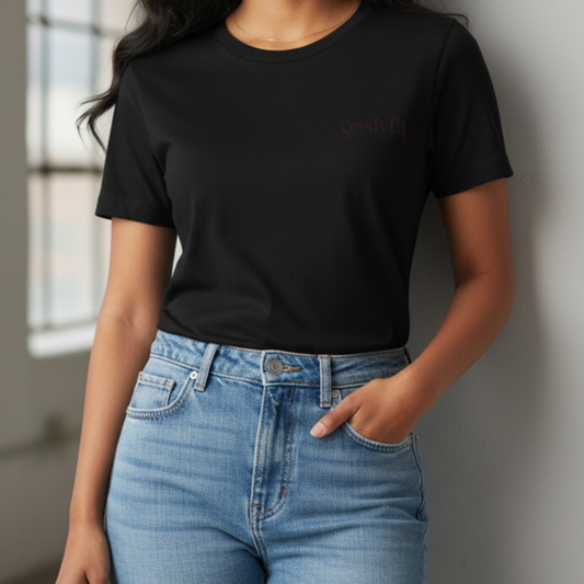 Person wearing a black t-shirt with text and blue jeans against a neutral background