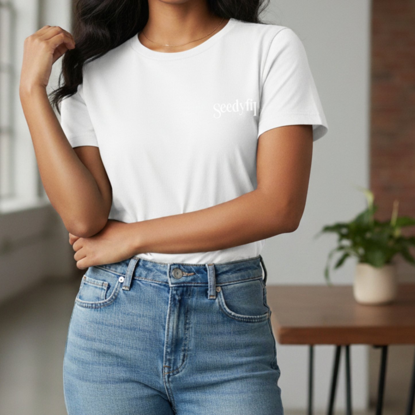 Person wearing a white t-shirt with text and blue jeans indoors